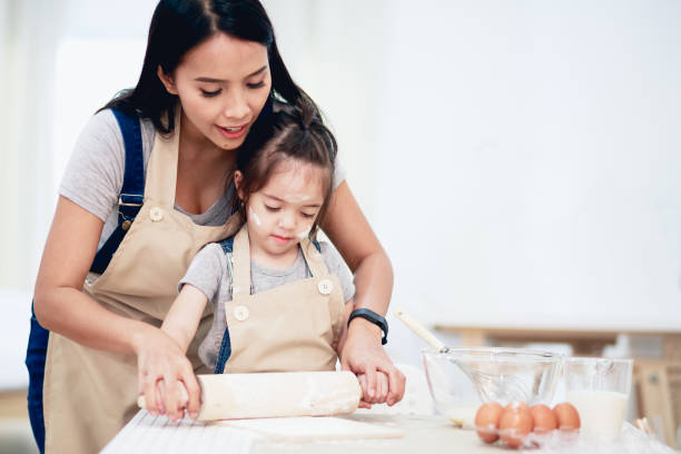 mère et fille à l'aide d'un rouleau à pâtisserie ensemble - rolling dough pastry apron photos et images de collection