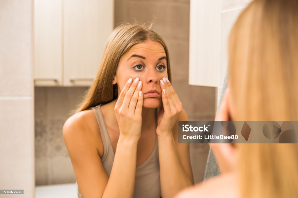 Woman looking eye bags Tired woman looking her eye bags in the bathroom. Eye Stock Photo