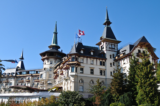 Beautiful houses in sunny summer day in Hallstatt town, Austria with mountain and blue sky clouds in background.