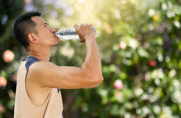 istock Man drinking water from bottle after running in a park 914081790