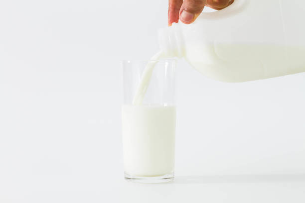 istock Hand pouring milk from bottle into glass on white background 914081848