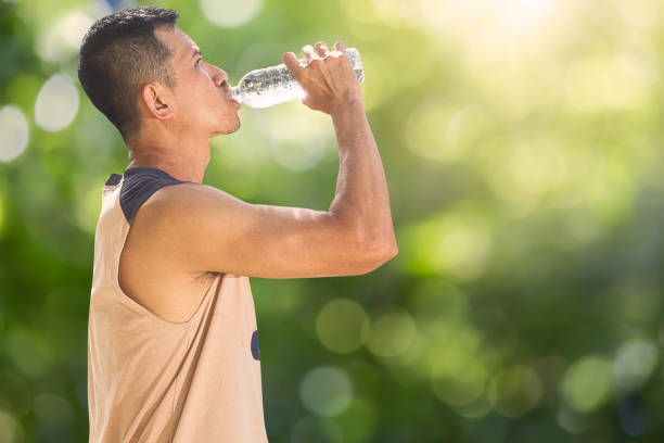 istock Man drinking water from bottle after running on blurred bokeh background 914082040