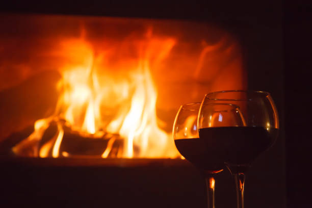 istock Two glasses of wine in front of log fire 914082256