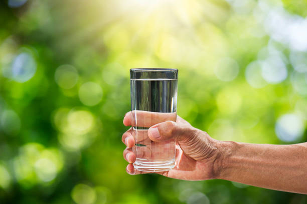 istock Hand holding drinking water in glass on blurred green bokeh background 914082796