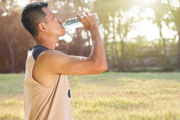 istock Man drinking water from bottle after running in a park 914082968