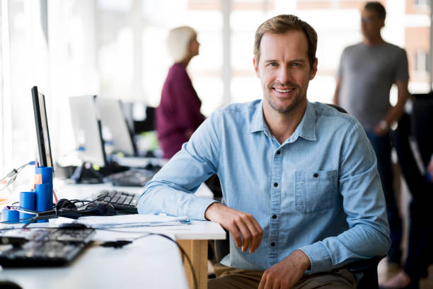 istock Smiling businessman sitting at computer desk 914093984