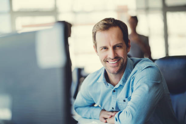 istock Smiling businessman sitting at computer desk 914094020