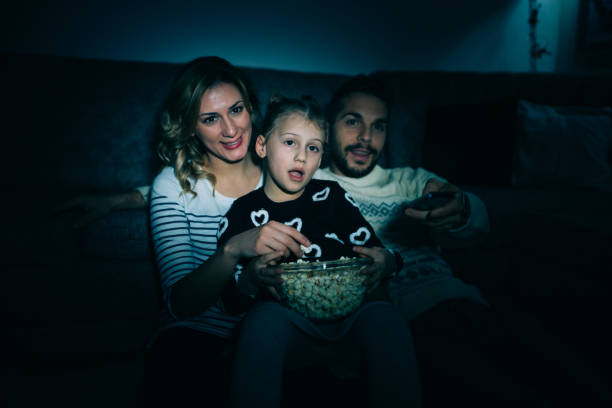 istock Family eating popcorn while watching tv at home 914097472