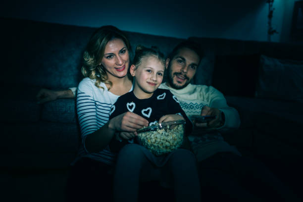 istock Family eating popcorn while watching tv at home 914099644