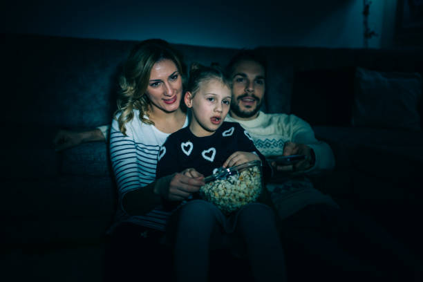 istock Family eating popcorn while watching tv at home 914099764