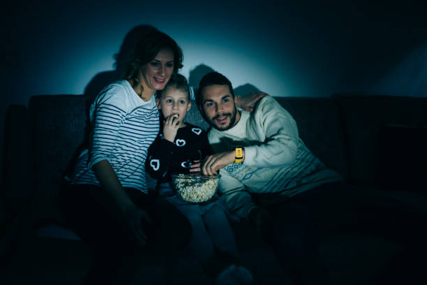 istock Family eating popcorn while watching tv at home 914099850