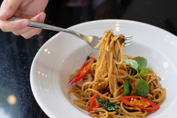 istock closeup people eating spaghetti in white dish 914103534