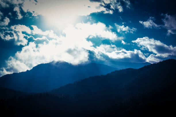 istock Mountain silhouettes on a cloudscape with rays of sun through the clouds 914118166