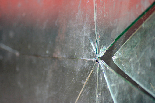 Broken security glass that once covered the window of a security checkpoint, now abandoned.  Belfast Northern Ireland.
