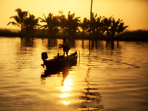Unrecognizable fisherman fishing in early morning, Kerala Backwaters. South India.