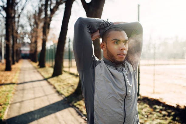 istock Sportsman warming up before run in autumn park 914145292