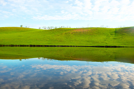 Morning on the lake with green hills and reflection.