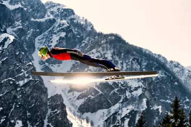 Side View of Young Male Ski Jumper in Mid-Air, Sun Reflection