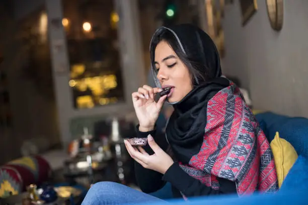 Arab woman in traditional clothing eating palm dates. About 25 years old, Middle Eastern female.