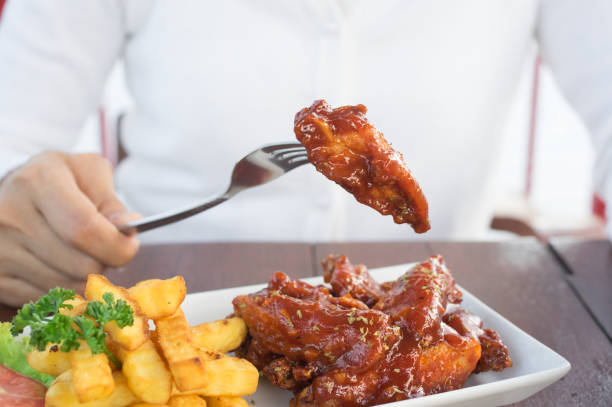 istock Girl eating chicken wing and potato chips. 914157704