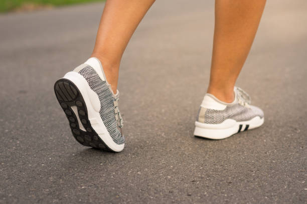 istock Female runner feet jogging on street. 914157836