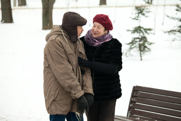 Senior man and woman on a walk in winter park Senior man and woman on a walk in winter park seria stock pictures, royalty-free photos & images