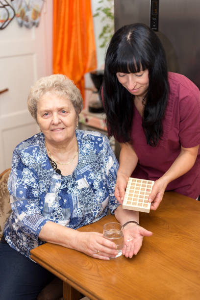 pflegerin versorgt seniorin mit tabletten - reha 뉴스 사진 이미지