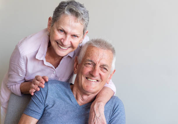 istock Older woman leaning on seated older man laughing 914191802