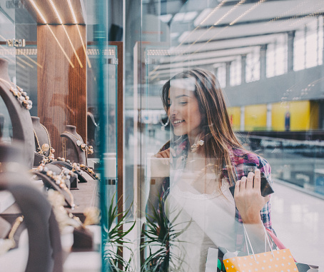 Young woman in the shopping mall looking at gorgeous jewellery on the shop window