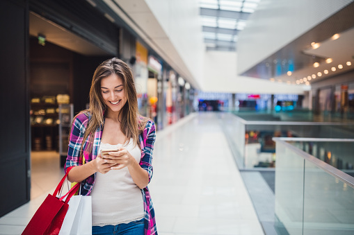 Young woman texting on phone in the shopping mall