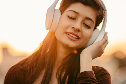 Young woman listening music in happy mood with back sunlight.