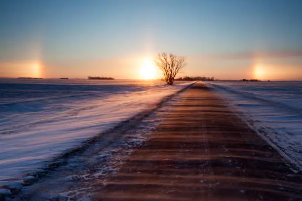 Just out side of Winnipeg, Manitoba, near the perimeter highway. A very cold evening, wind blowing over the road. Long exposure to capture the snow blowing , Sundogs, Image taken from a tripod.