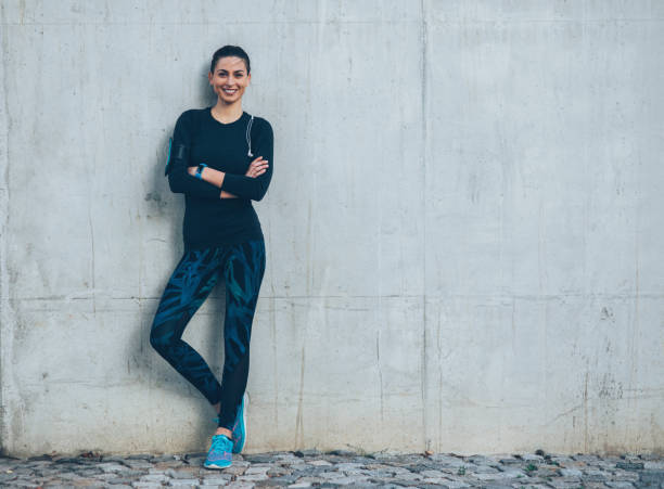 Sportswoman resting Sportswoman resting on a wall outdoors. sportswear stock pictures, royalty-free photos & images