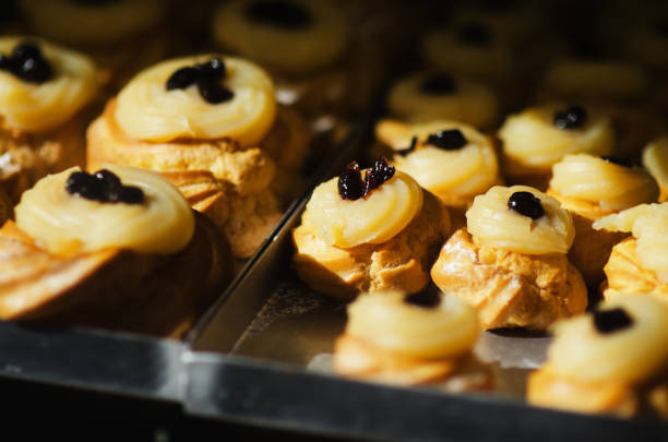 Tray of fresh baked Italian zeppole di San Giuseppe, pastries filled with lemon pastry cream and topped with Amarena cherries, at a bakery in Naples, Italy