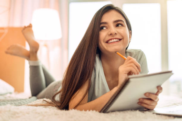 istock Cheerful teenage girl thinking what to write in notebook 914245326