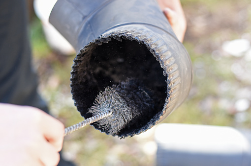 Man cleaning chimney pipe outside. Chimney sweep cleaning