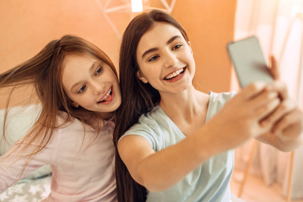 istock Pretty teenage girls having fun while taking selfies 914249680