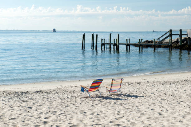 Chairs on beach with a lighthouse in background in New London, Connecticut, USA. New London has been an important port city since Revolutionary War in US.