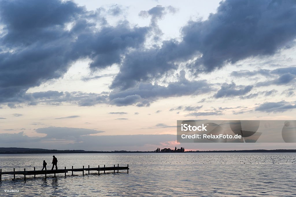 Mère et fils marche sur un ponton au bord du lac (XXL) après le coucher du soleil - Photo de Famille libre de droits
