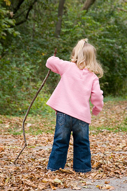 istock Little girl poking the Fall leaves with a stick 91429749