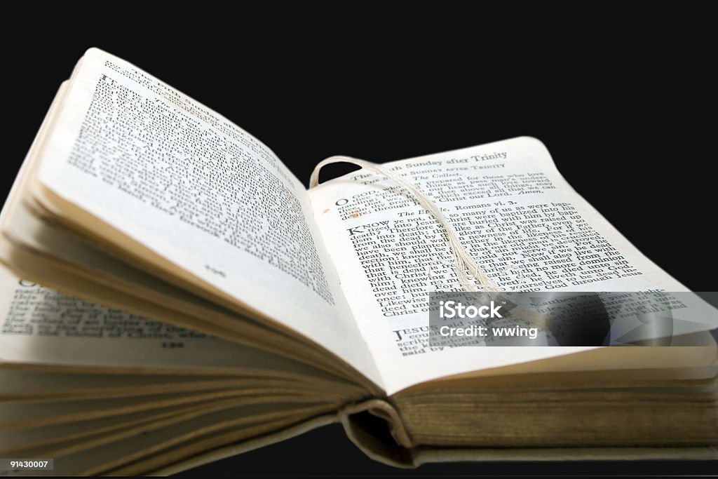 Closeup of an open vintage Missal with a string placeholder. A antique religious missal open to a daily reading. Copy space and isolated on a black background. Antique Stock Photo