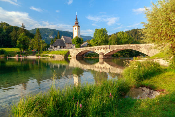 igreja de sv. john the baptist e uma ponte à beira do lago bohinj - bohinj - fotografias e filmes do acervo