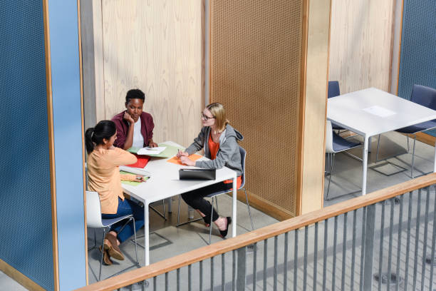 three female students discussing around table in booth, elevated view - 1750 imagens e fotografias de stock