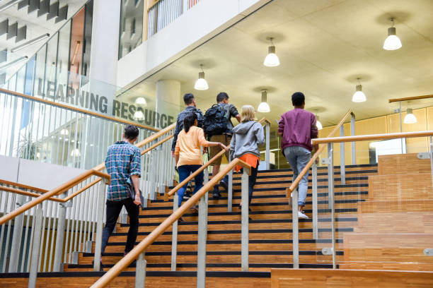 istock Six students walking up wooden steps in modern college building 914314270