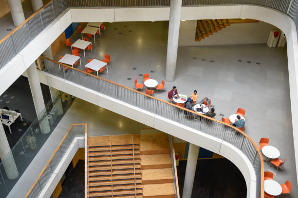 istock Students sitting on elevated area in modern college 914314278