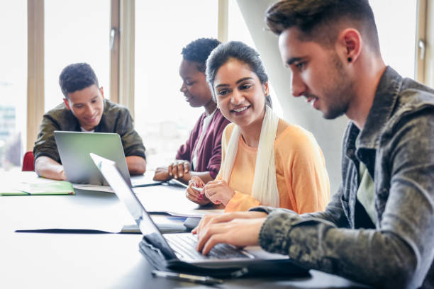 hombre joven con laptop estudiante mirando y sonriendo - inglaterra fotografías e imágenes de stock