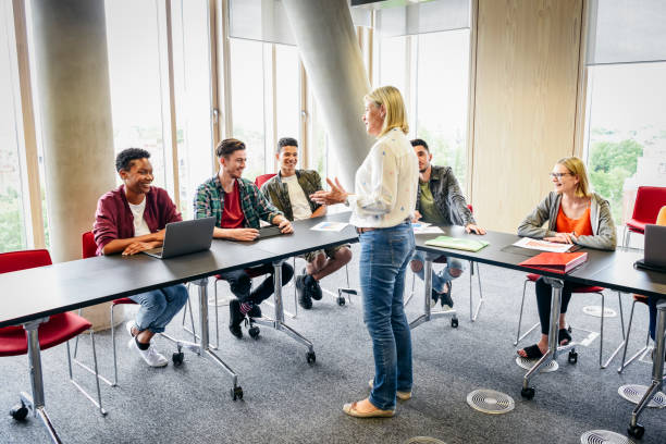 モダンな建物の大学生のクラスを教える熟女 - england talking classroom education ストックフォトと画像