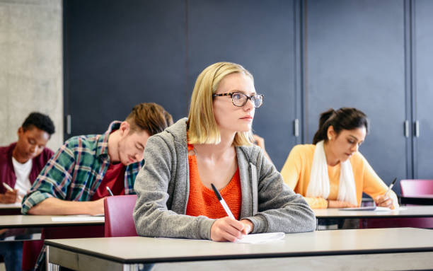 istock Young woman doing exam in classroom, looking up, thinking 914314340