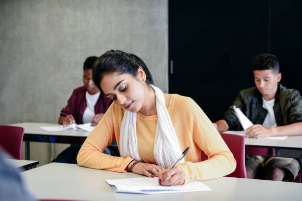 Young woman taking an exam writing at desk in classroom