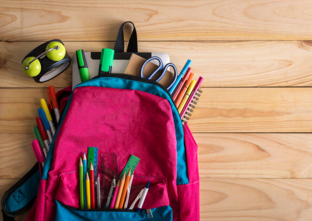 istock School backpack with school supplies and clock on wooden table. 914326874